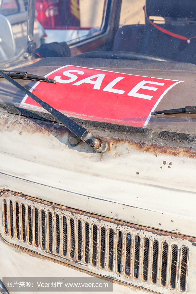 旧旧的汽车挡风玻璃上的红色销售标志,汽车零配件市场。